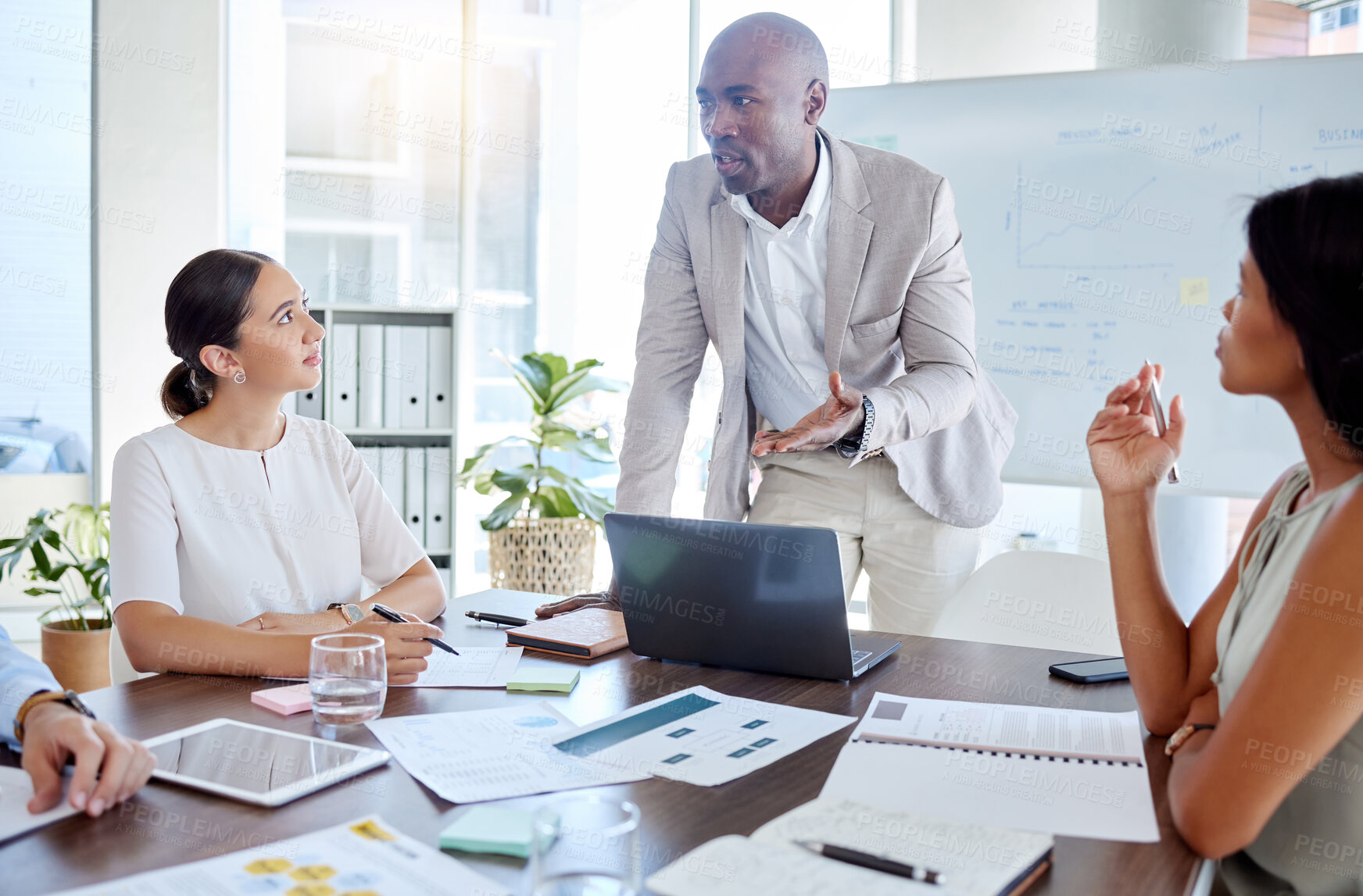 Buy stock photo Business, black man and speaker, presentation leader and planning with business people in meeting. Diversity, laptop and paperwork, talking and listening to corporate pitch and project strategy.