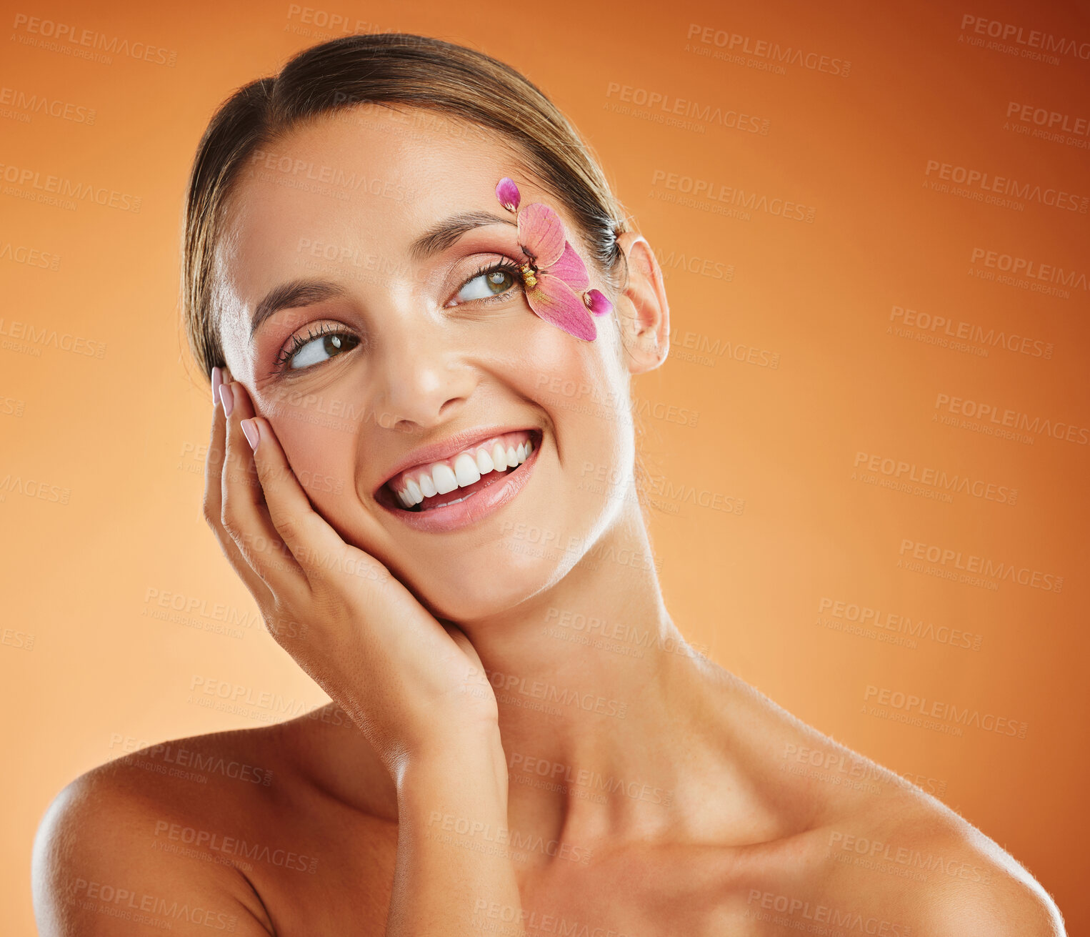 Buy stock photo Model, flower and eye with makeup in studio with smile for fashion, cosmetics or beauty against backdrop. Woman, orchid and floral art for eyes with skincare, happy and face orange background