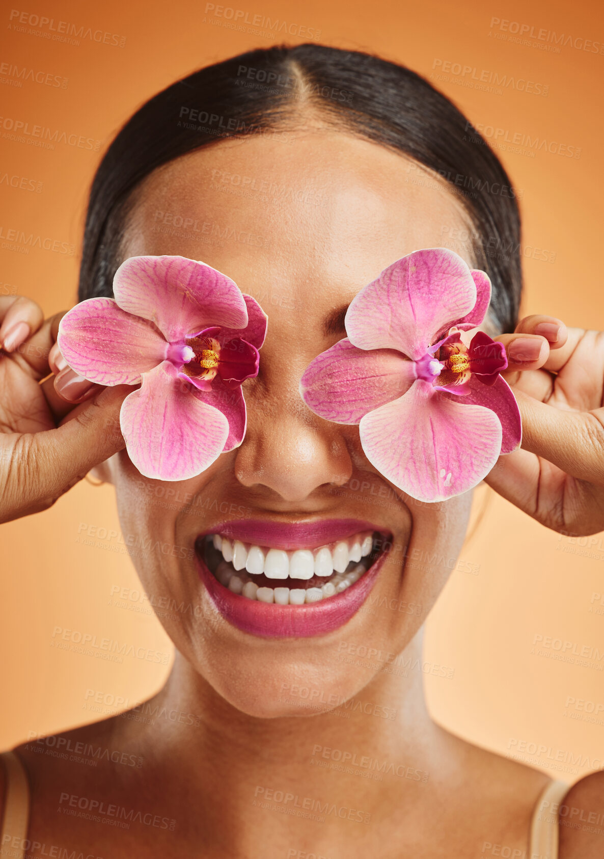 Buy stock photo Orchid flower, creative art and beauty woman with makeup, cosmetic and smile on face against an orange background. Happy, floral and comic female model with plant for facial wellness and skincare 
