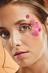 Woman, flower and beauty eye makeup in portrait for cosmetics, skincare and facial wellness mockup in studio against orange background. Model, cosmetic art and orchid petals design for spring fashion