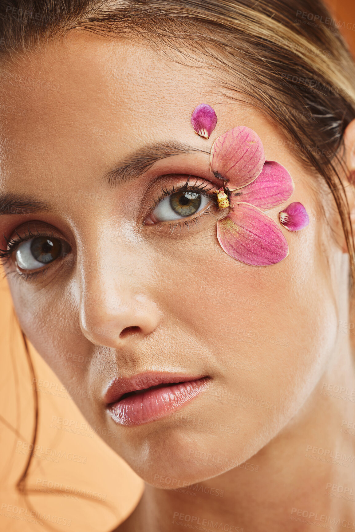 Buy stock photo Woman, flower and beauty eye makeup in portrait for cosmetics, skincare and facial wellness mockup in studio against orange background. Model, cosmetic art and orchid petals design for spring 