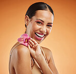 Skincare, beauty and flower with a model black woman in studio on an orange background to promote a natural product. Cosmetics, face and plant with an attractive young female posing for wellness