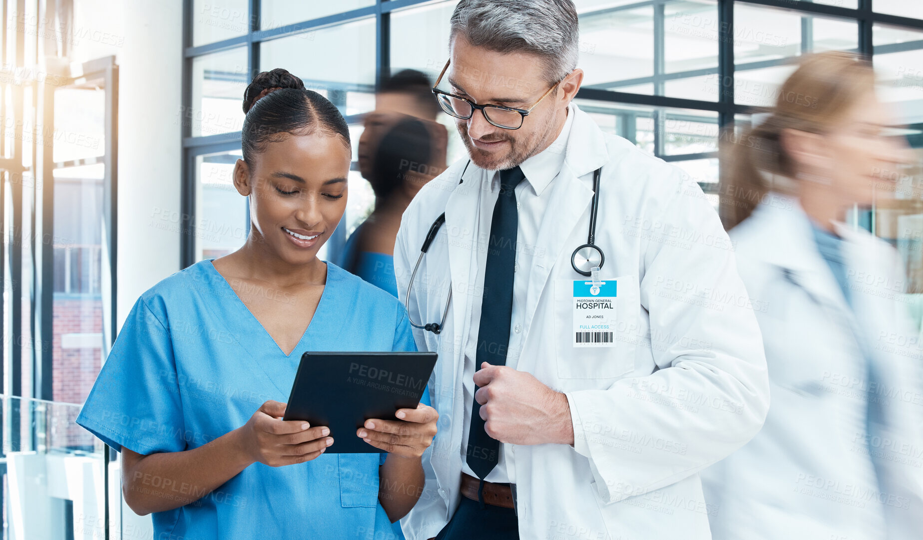 Buy stock photo Medical doctors, tablet and busy hospital with conversation, online research and talking about results in clinic. Digital device, healthcare and technology for communication, smile and agreement.