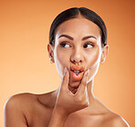 Beauty, makeup and cosmetics with woman using hands to pout lips with makeup for cosmetology advertising against orange background. Face of female model showing tint, mouth and colour for skincare