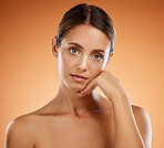 Skincare, beauty and portrait with hand pose and serious face of beautiful woman with glowing body. Model girl at orange background with natural, young and cosmetic feeling on skin in studio.

