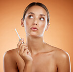 Skincare, beauty product and woman holding makeup brush for lipstick, gloss and cosmetics for shine. Female thinking of dermatology or cosmetology skin treatment against orange studio background
