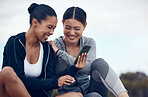 Fitness, relax and friends on phone after exercise networking on social media with technology. Sports training, workout and women laughing at funny comic video online with smartphone in outdoor park.