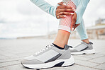 Fitness, shoes and injury with a sports woman holding her leg in pain during exercise or a workout outdoor in the city. Training, anatomy or accident with a female athlete suffering from inflammation