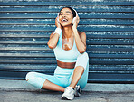 Fitness, music and happy woman with headphones sitting on ground for outdoor workout or running break. Sports, exercise and listening to streaming app on earphones enjoying favorite training playlist