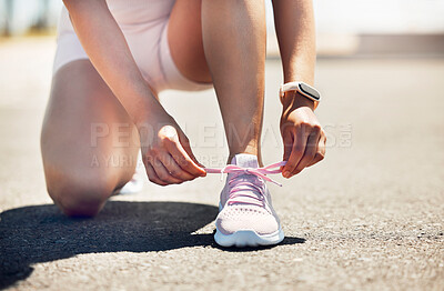 Buy stock photo Fitness, exercise and shoes with a sports woman tying her laces while running on an asphalt road or street. Workout, training and cardio with a female athlete getting ready for a run routine