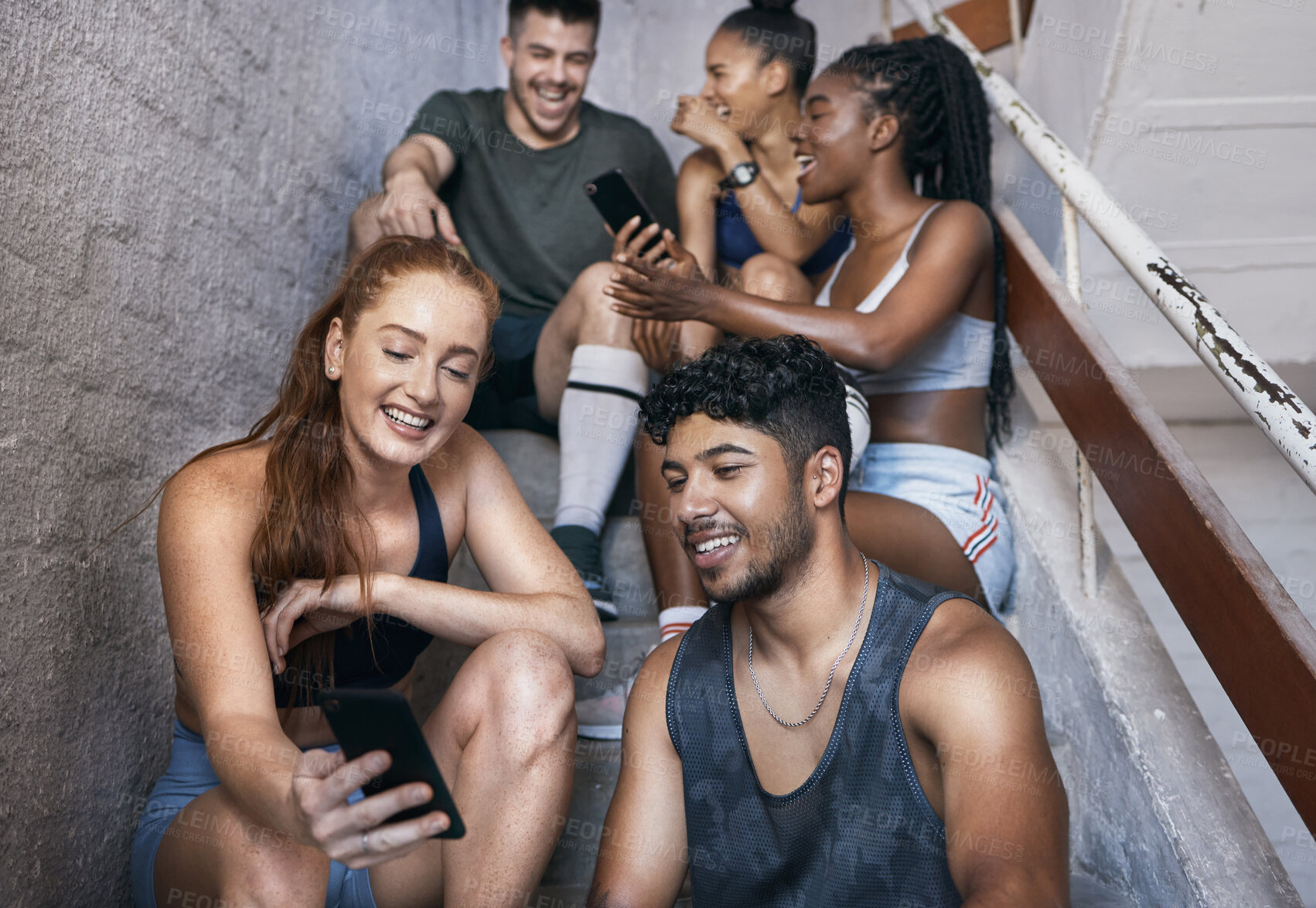 Buy stock photo Fitness, phone and group of friends on stairs networking on social media together after gym workout. Happy, smile and sports people sitting and watching funny comic videos on internet with smartphone