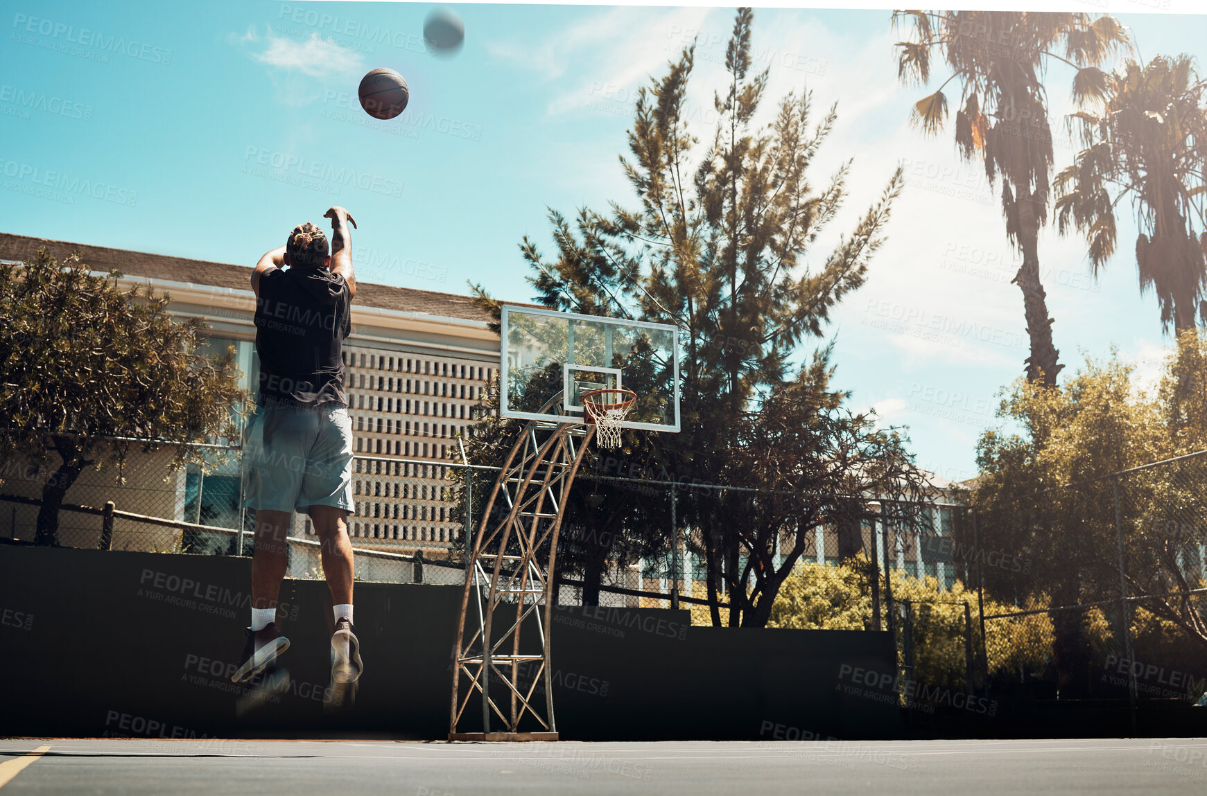 Buy stock photo Basketball, outdoor and a man shooting ball alone on basketball court in Miami summer sun. Fitness, training and health, basketball player jumping to score on court at weekend sports game practice.