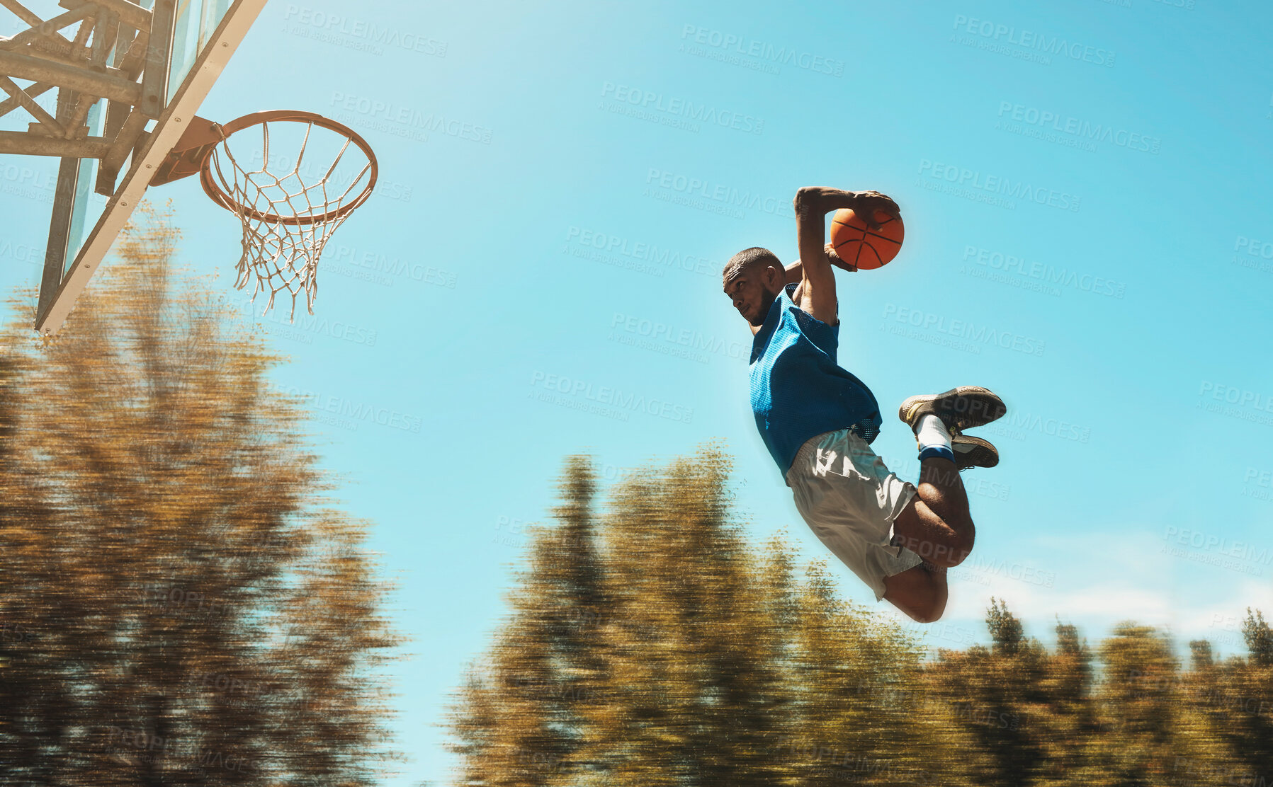 Buy stock photo Basketball, sports and dunk with a man athlete jumping or flying through the air to score while playing on an outdoor court against the sky. Sport, fitness and exercise with a male basketball player