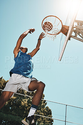 Basketball, sport and man with a goal during a game, professional event or training on an outdoor court in summer. Low view of an athlete in the air to score during sports for fitness and exercise