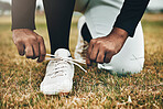 Baseball, sports and shoes with a man athlete tying his laces on a grass pitch or field for training, a game or a match. 