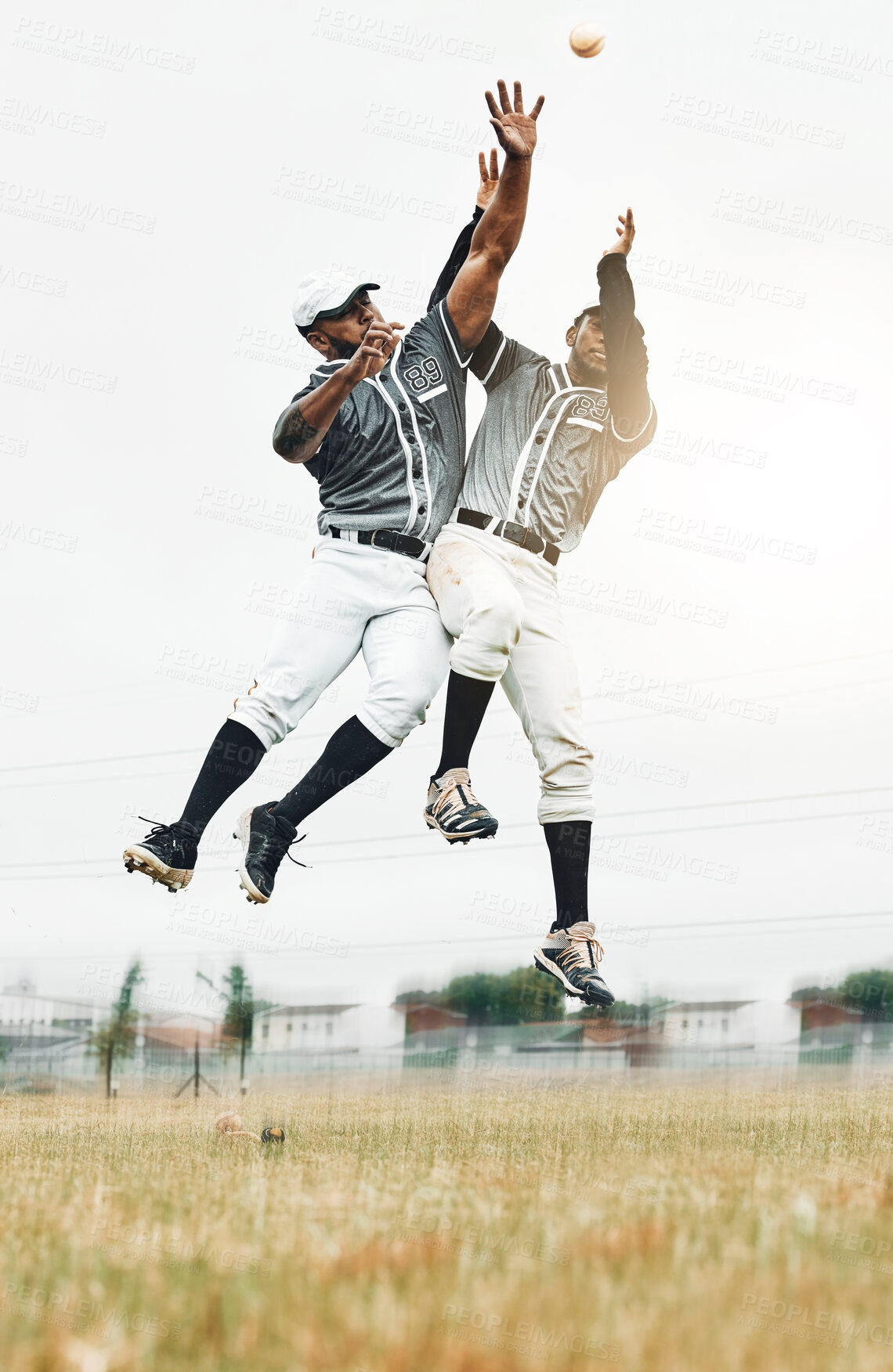 Buy stock photo Sports, baseball and men jump to catch ball on field during game, action and motion with teamwork. Fitness, baseball team and black man jumping with teammate to help with catching for strike out.