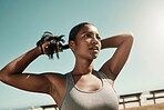 Woman tying her hair before an outdoor workout for fitness, health and wellness in nature. Training, sports and healthy girl athlete from Mexico preparing for a run or cardio exercise in a field. 