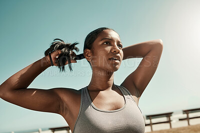 Buy stock photo Woman tying her hair before an outdoor workout for fitness, health and wellness in nature. Training, sports and healthy girl athlete from Mexico preparing for a run or cardio exercise in a field. 