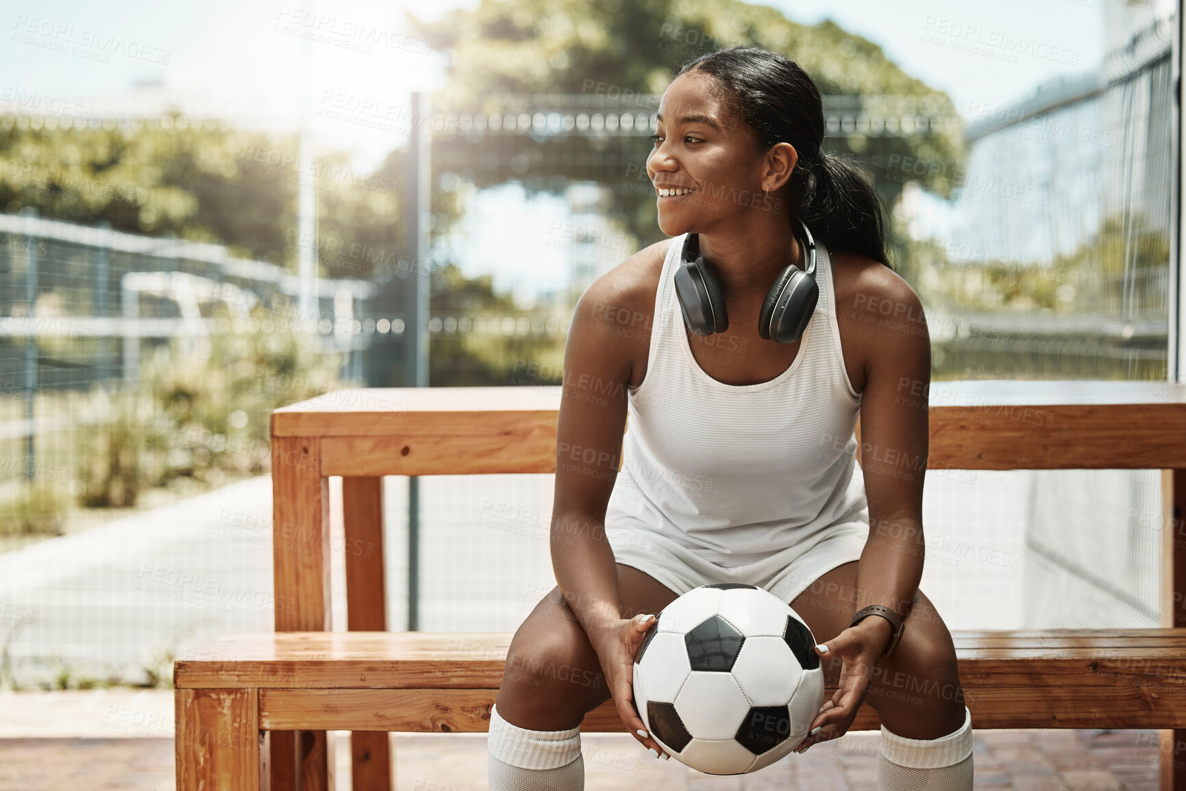 Buy stock photo Sports, soccer and a woman on bench with ball in city park in Sao Paulo. Fitness, fun and a happy black woman in Brazil sitting, holding soccer ball and watching a game in summer sun with headphones