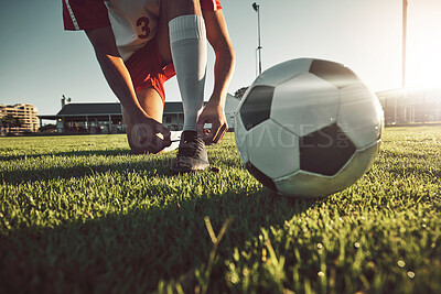 Soccer, ball and tying shoes for sports day of player on the grassy field for match, game or competition. Football professional in motivation getting ready for sport activity, fitness and exercise