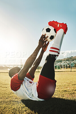 Soccer, sports and stretching with a black man athlete training with a ball before a game or match outdoor. Football, fitness and workout with a male getting ready for sport on a grass pitch or field