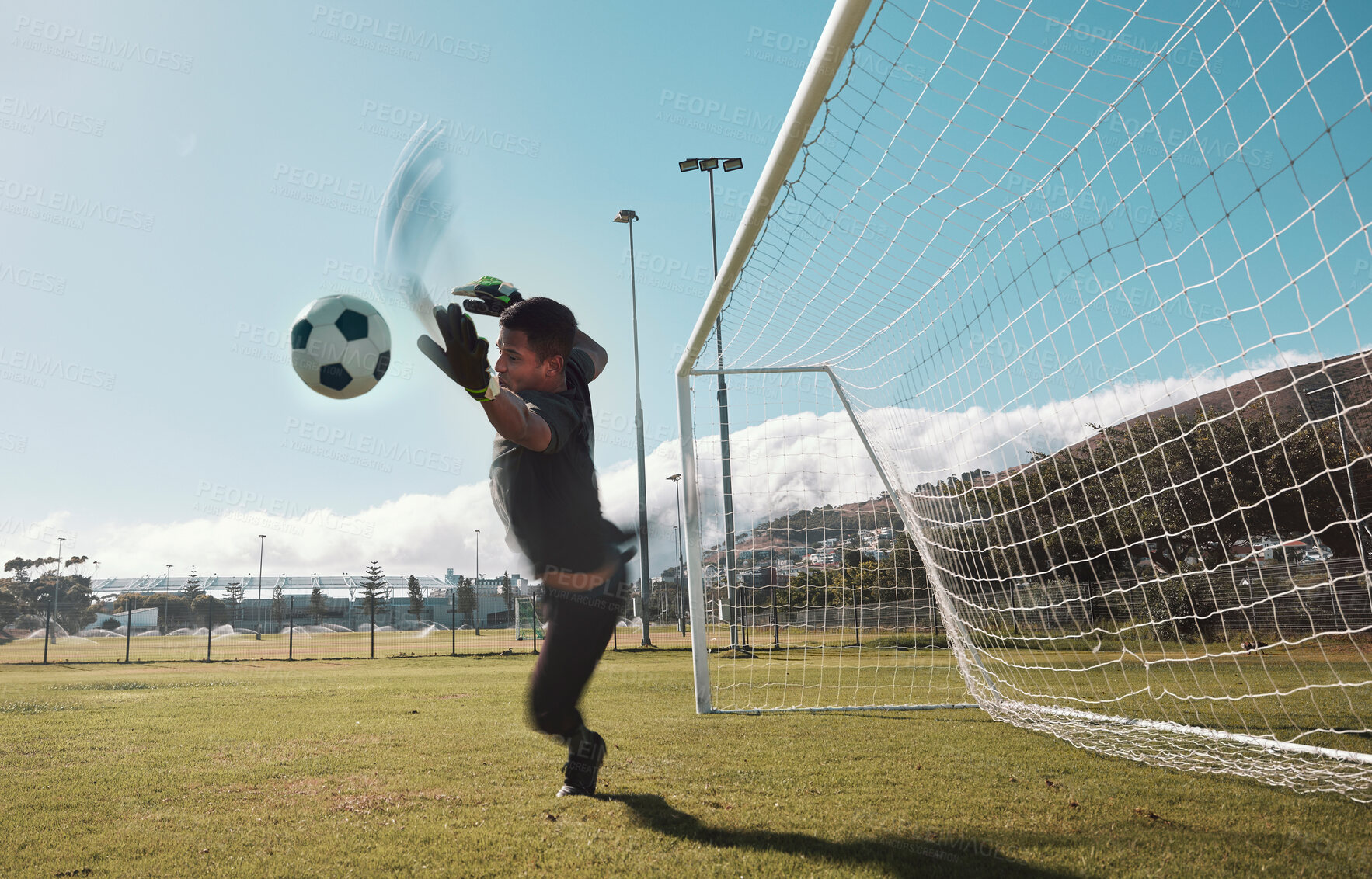 Buy stock photo Goalkeeper, soccer and man jumping for the ball to save the goals by the score post at an outdoor field. Fitness, football and healthy male goalie playing or training with energy for the sports game.