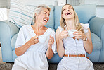 Coffee, mother and daughter with comic communication together on the living room floor of their house. Funny, happy and elderly mom with her child, tea and conversation in the lounge of their home