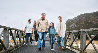 Buy stock photo Family, walking and travel with a girl and grandparents holding hands on a pier while on holiday or vacation together. Love, trust and children with a man, woman and granddaughter boding on a walk