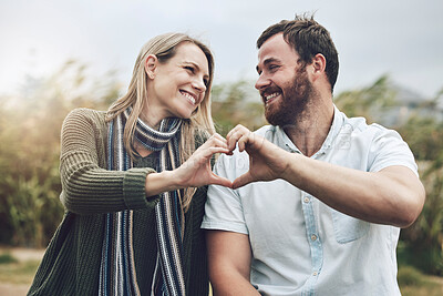 Buy stock photo Couple, hands and smile with love gesture for happy relationship bonding and care in the outdoors. Hand of man and woman smiling together in happiness with heart shape sign for romance in nature park
