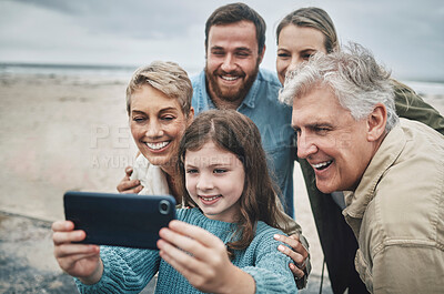 Buy stock photo Family, selfie and girl with phone on beach for holiday, vacation or journey together by ocean. Group, mom and dad with child, grandparents and smartphone for photo in winter with smile by sea