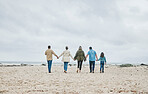 Big family, beach holiday and summer travel with child, parents and grandparents on sand and cloudy sky for love, care and support. Men, women and girl kid walking together holding hands on vacation