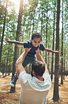 Forest, love and adoption son with father playing airplane wings or flying in air game together. Foster, interracial and family with black kid enjoying bonding with caucasian dad in Canada nature.
