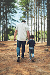 Grandfather, child and hold hands for walk in forest, nature or woods together for bonding. Man, senior and kid by trees, sunshine and summer for walking, fun and happiness on vacation with family