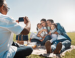 Family, phone and picnic photo with smile, hug and happy together in summer on grass in a park. Grandparents, mother and children with smartphone, social media and online during break on weekend