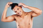 Beauty, hair and grooming with a man using a brush or comb in studio on a gray background for hairstyle. Style, happy and smile with a handsome young male getting ready with a haircare routine