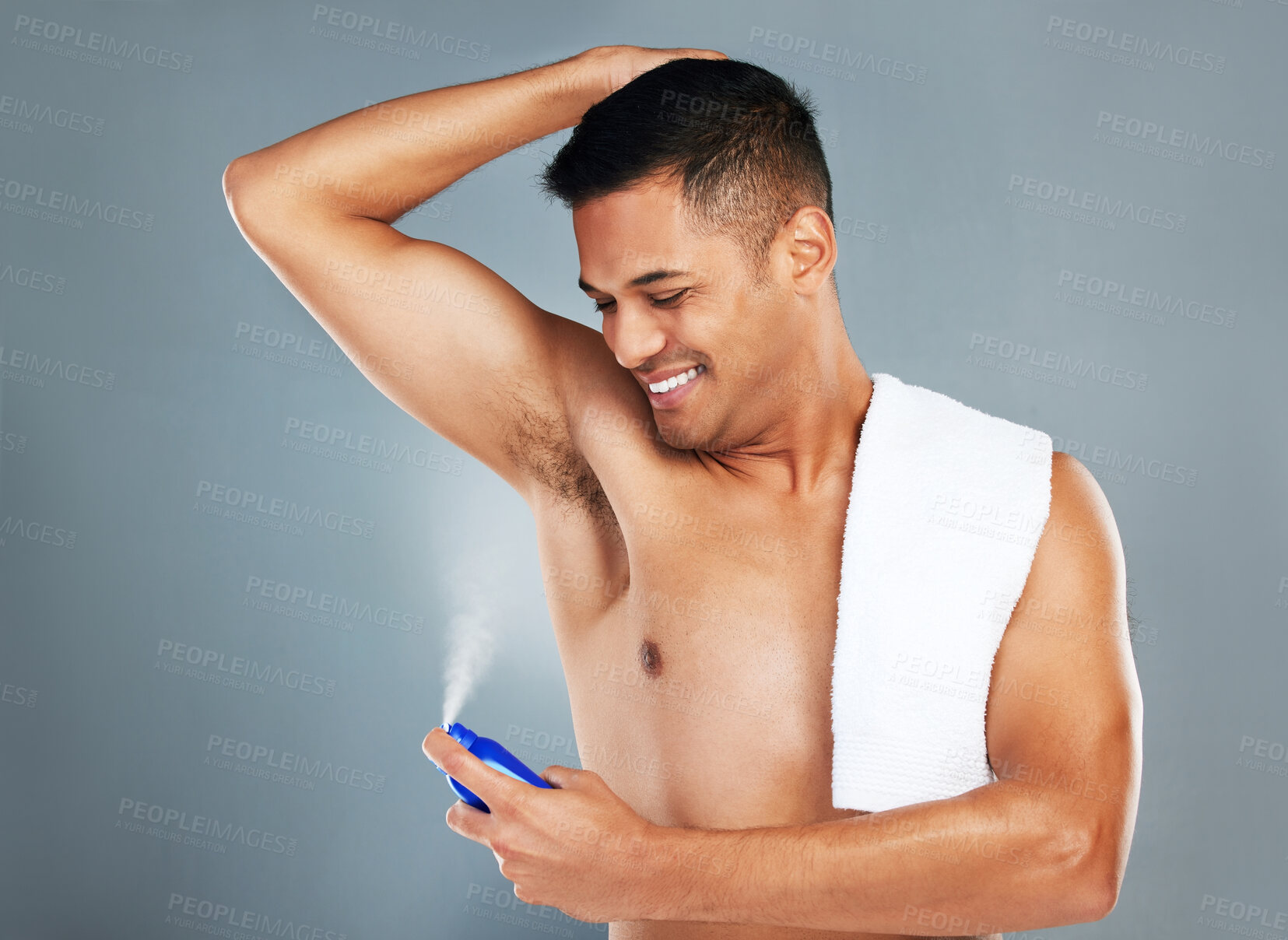 Buy stock photo Man, smile and spray with deodorant on skin in studio for fragrance, hygiene and fresh scent. Model, happy and underarm with happiness to stop sweat, odor and smell on armpit on grey background