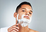 Man, razor and skincare in beauty for grooming, shave or clean hygiene against a grey studio background. Male face shaving beard with cream, cosmetics and care for healthy or fresh skin