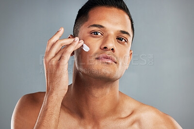 Buy stock photo Beauty, skincare and man with cream on his face using skincare products, lotion and moisturizer. Facial, wellness and healthy skin of young male with beauty products for men in grey background studio