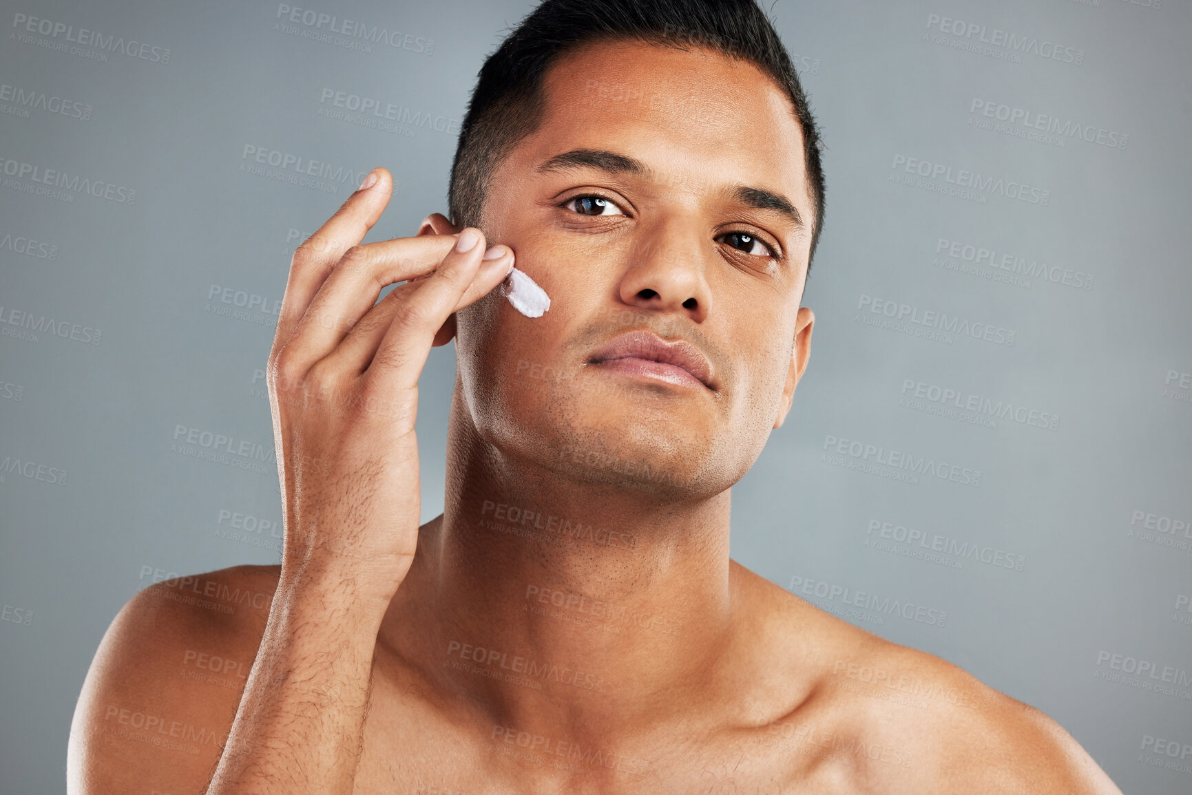 Buy stock photo Beauty, skincare and man with cream on his face using skincare products, lotion and moisturizer. Facial, wellness and healthy skin of young male with beauty products for men in grey background studio