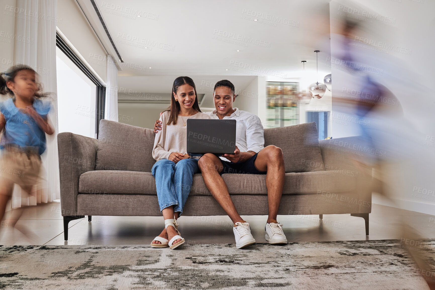 Buy stock photo Family, laptop and children running in living room in home with motion blur having fun. Energy, kids and relax of man, woman and parents sitting on sofa with computer, streaming movie or web surfing.