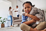 Sad, little girl and teddy hug crying from parents in fight, argument or divorce at home. Unhappy young child in depression, stress and anxiety from mother and father fighting in family disagreement