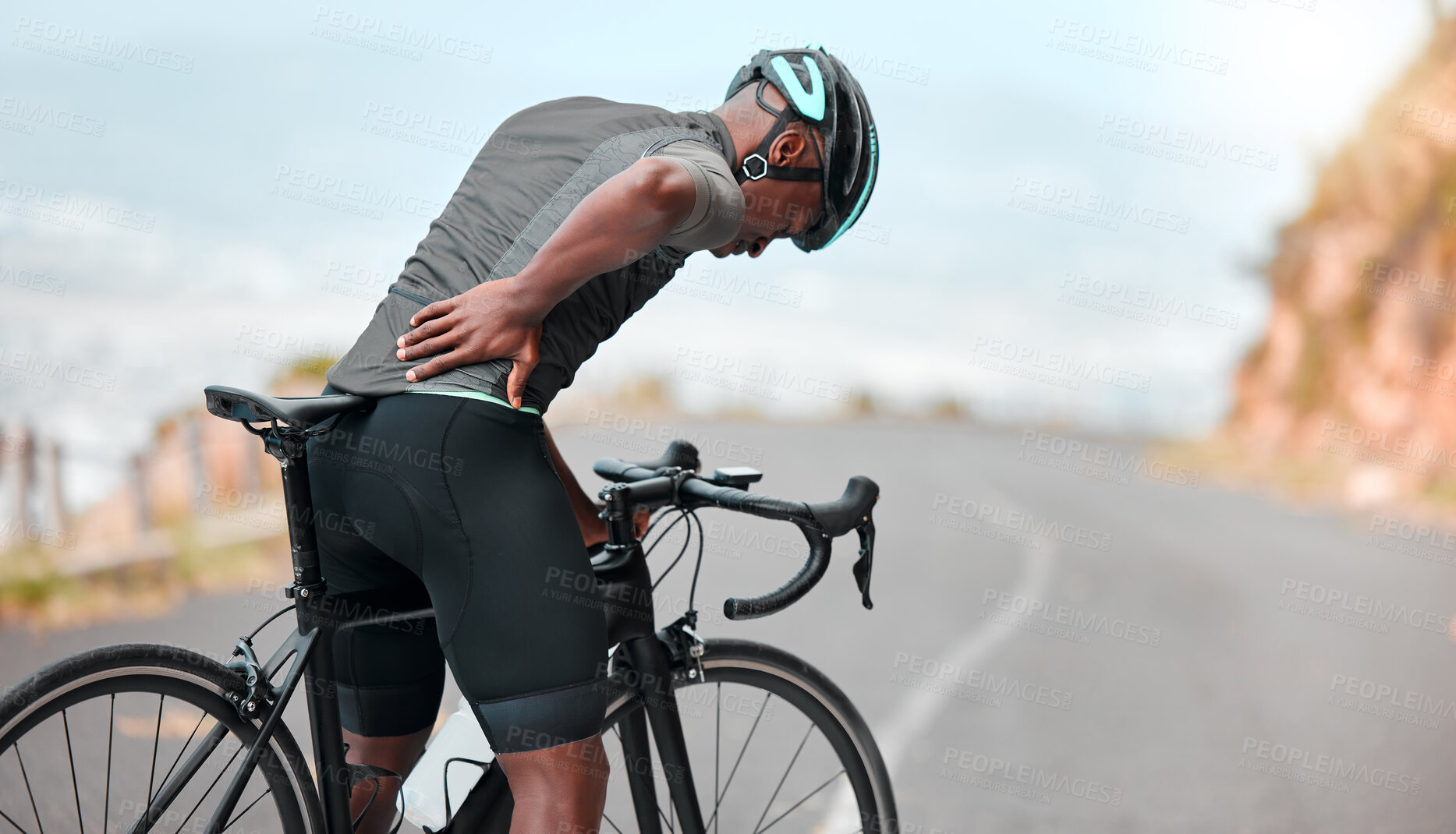 Buy stock photo Fitness, sports injury and back pain by man cyclist feel uncomfortable while cycling along mountain route. Training, pain and injured athletic guy suffering from joint, muscle and spinal discomfort