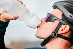 Fitness, cycling and man drinking water in bottle during a cycle marathon, training or exercise. Cardio, sports and thirsty biker athlete enjoying a refreshing drink, liquid or beverage while biking.