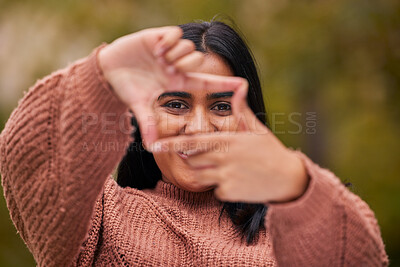 Buy stock photo Hands frame, woman and eyes look through fingers while framing happy facial expression. Portrait of young indian girl, pose behind hand gesture and smile against blur bokeh nature background outside