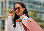 Shopping bag, retail and portrait of woman with sunglasses walking in city after store sale or discount. Happy, smile and rich posh housewife from Mexico shopping for fashion clothes in urban town.