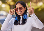 Music, headphones and peace hand sign of a woman from mexico in nature on a walk. Portrait of a person with a happy smile, sunglasses and web streaming audio outdoor feeling free in a nature park