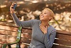 Park bench, phone selfie and black woman in nature outdoors taking picture. Happy, smile and girl from South Africa with 5g mobile for photo, social media post or comic memory alone at park outside.
