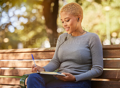 Buy stock photo Woman, earphone and writing in book, diary or journal in a park outdoor with a happy smile on a bench. Latino girl write idea, goals and vision in a notebook in summer while relax or smiling alone