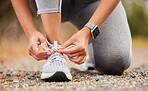 Shoes, fitness and exercise with a sports woman tying her laces before training, running or a workout. Hands, health and cardio with a female runner or athlete getting ready for an endurance run 