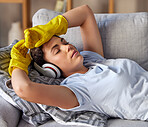 Sofa, headphones and woman cleaner sleep, relax and listening to music after cleaning work in home living room. Calm, tired and fatigue girl on a couch in her lounge with audio streaming service app